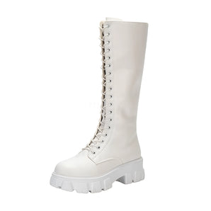 Women's white knee-high lace-up combat boots with platform sole worn by a person, showcasing the boot's design and height.