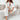 
A woman wearing a white linen jumpsuit with a deep V-neck and a drawstring waist, styled for summer chic.