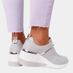 Women's white platform sneakers with zipper, featuring a stylish design suitable for walking, shown on feet against a purple background.