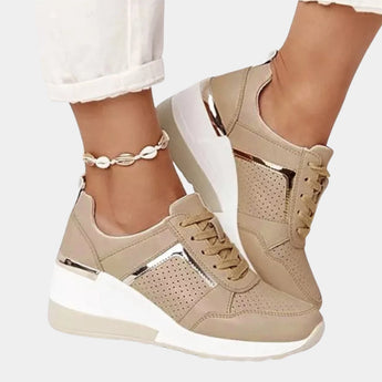 Women's brown platform sneakers featuring a white upper and stylish zipper, shown on a model's foot, highlighting their fashion-forward design and suitability for walking.