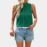 
A woman wearing a white pleated high neck blouse paired with distressed denim shorts.