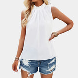 Women's white pleated high neck blouse paired with distressed denim shorts, showcasing a stylish and casual outfit.