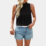 A woman wearing a white pleated high neck blouse paired with distressed denim shorts.