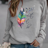 Women's white sweatshirt featuring a "Let It Be" feather print in a bohemian style, paired with jeans. The sweatshirt has long sleeves and a round neckline, embodying a casual yet fashionable look.