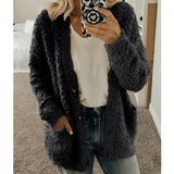 Women's black teddy coat, soft plush fabric, oversized fit, featuring a fluffy texture and long sleeves, styled with a fashionable look.