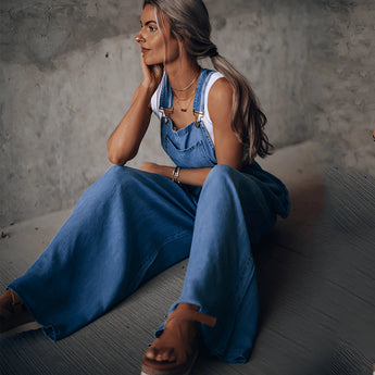 Women's wide-leg blue denim overalls with pockets, featuring a relaxed fit and classic design, worn by a person standing upright.