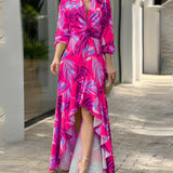 Pink floral V-neck wrap dress with a tropical print and high-low hemline, featuring sleeves and accentuating the waist, modeled in size 3XL.