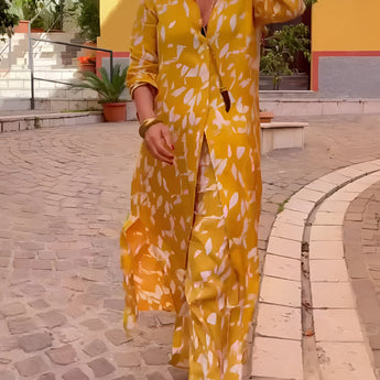 Yellow floral women's loungewear set featuring a long-sleeve pajama design with vibrant orange and yellow floral patterns. The set has a comfortable fit around the waist and sleeves, showcased in a fashion-forward photograph.