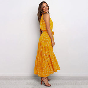 Yellow polka dot halter neck tiered maxi dress being worn by a woman, showcasing the summer elegance style with focus on the intricate design of the dress and the way it fits the human body.
