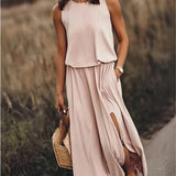 A fashion model wearing a yellow sleeveless maxi dress with a high slit, showcasing its flowy summer beachwear style. The dress features a fitted waist and a one-piece design, ideal for day wear.