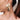 Gold shell earrings displayed on a woman's ear, showcasing unique ocean-inspired abstract jewelry design.